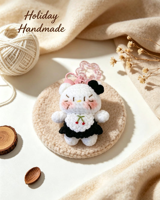 Handmade crochet kitty charm with black beret and cherry dress in a cozy holiday scene